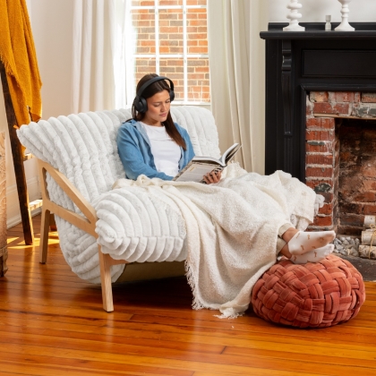 Woman wearing headphones and reading a book on Pillow Saxx chair