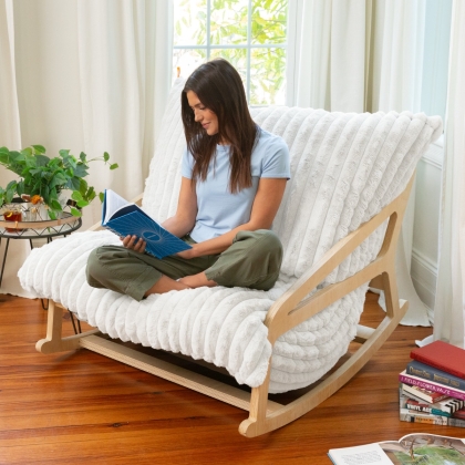 Young woman reading while sitting on white fur fabric Pillow Saxx rocking chair
