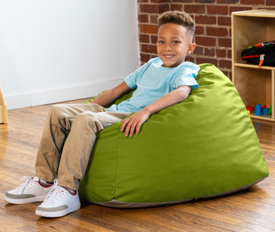 Boy in classroom on green Gumdrop bean bag chair